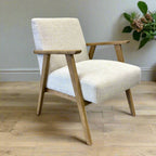 Side profile of the Ascot armchair in Oat with textured linen upholstery and tapered oak legs.