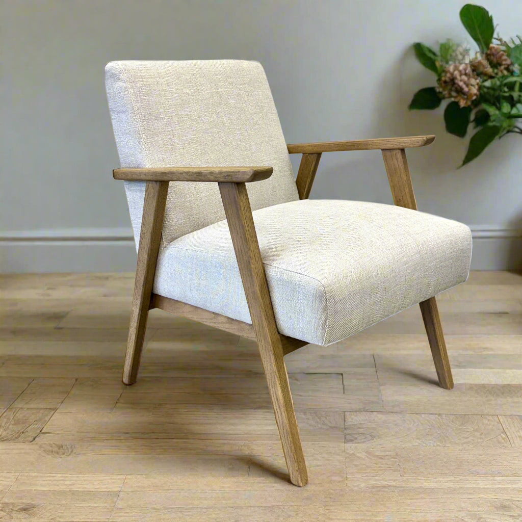 Side profile of the Ascot armchair in Oat with textured linen upholstery and tapered oak legs.