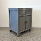 Angled view of Far East glossy grey bedside cabinet with drawer, two doors and brass handles