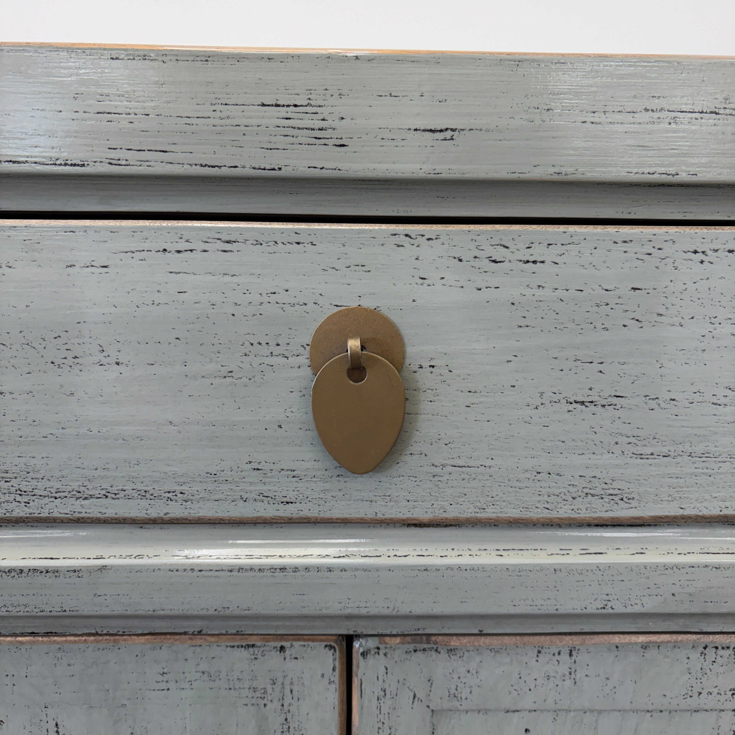 Close-up of distressed sage grey lacquer finish and brass handle on Far East Bedside