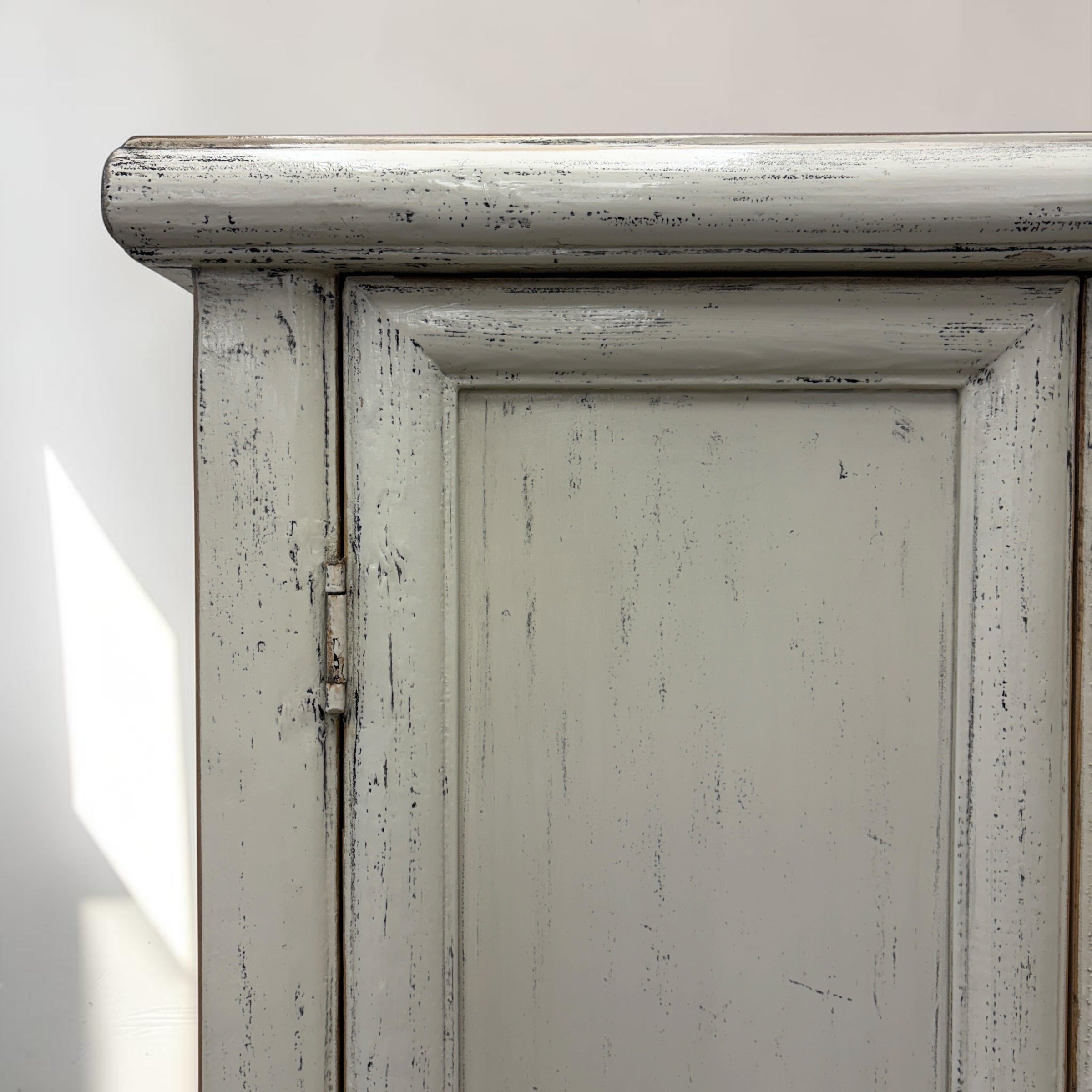 Close-up of Lina cupboard showing distressed white painted finish and panelled door detailing