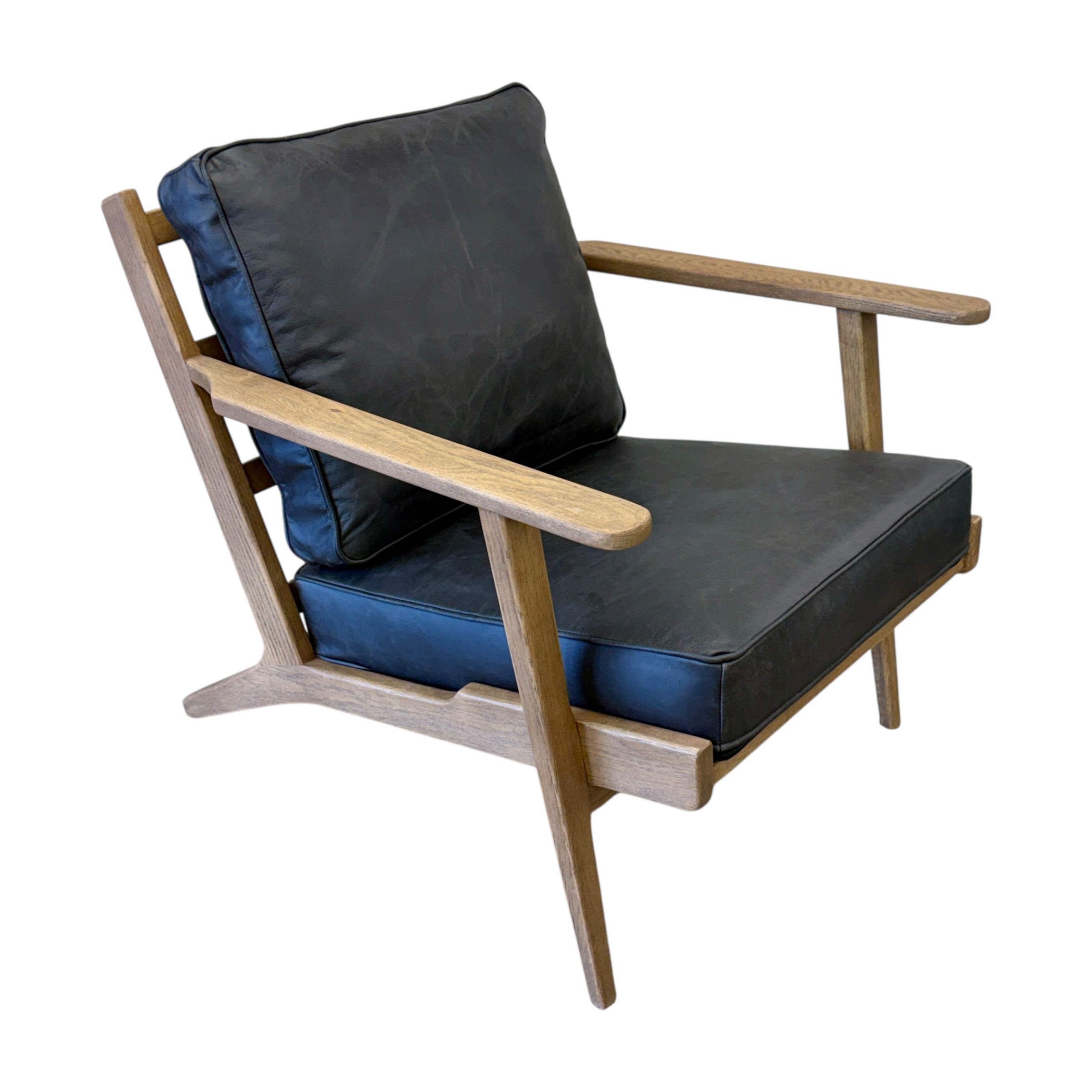 Side profile of the Nero armchair, showcasing its contemporary silhouette and leather upholstery.