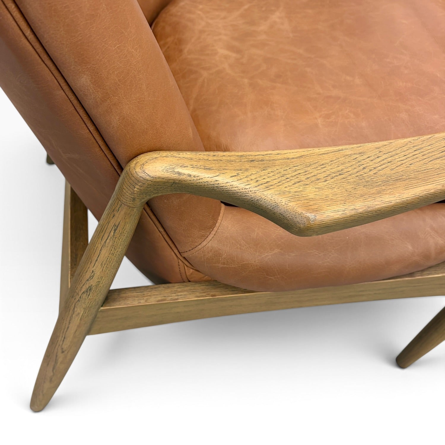 Close-up of Portobello Chair showing the sculpted solid oak arm, natural timber grain and toffee leather