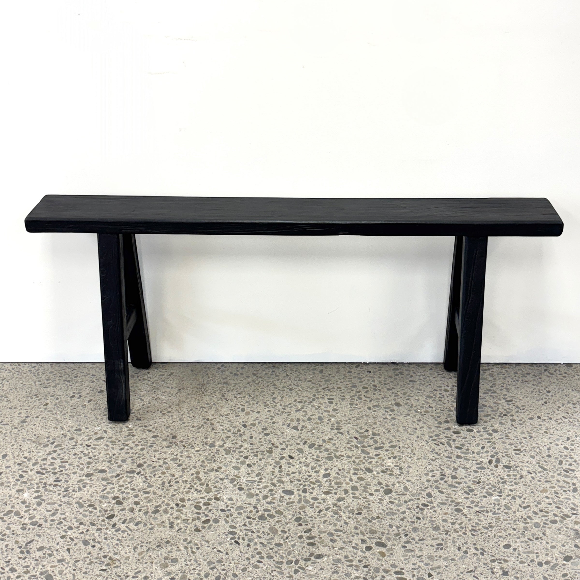 Black rustic elm Sammy Bench with long narrow seat and traditional trestle-style base