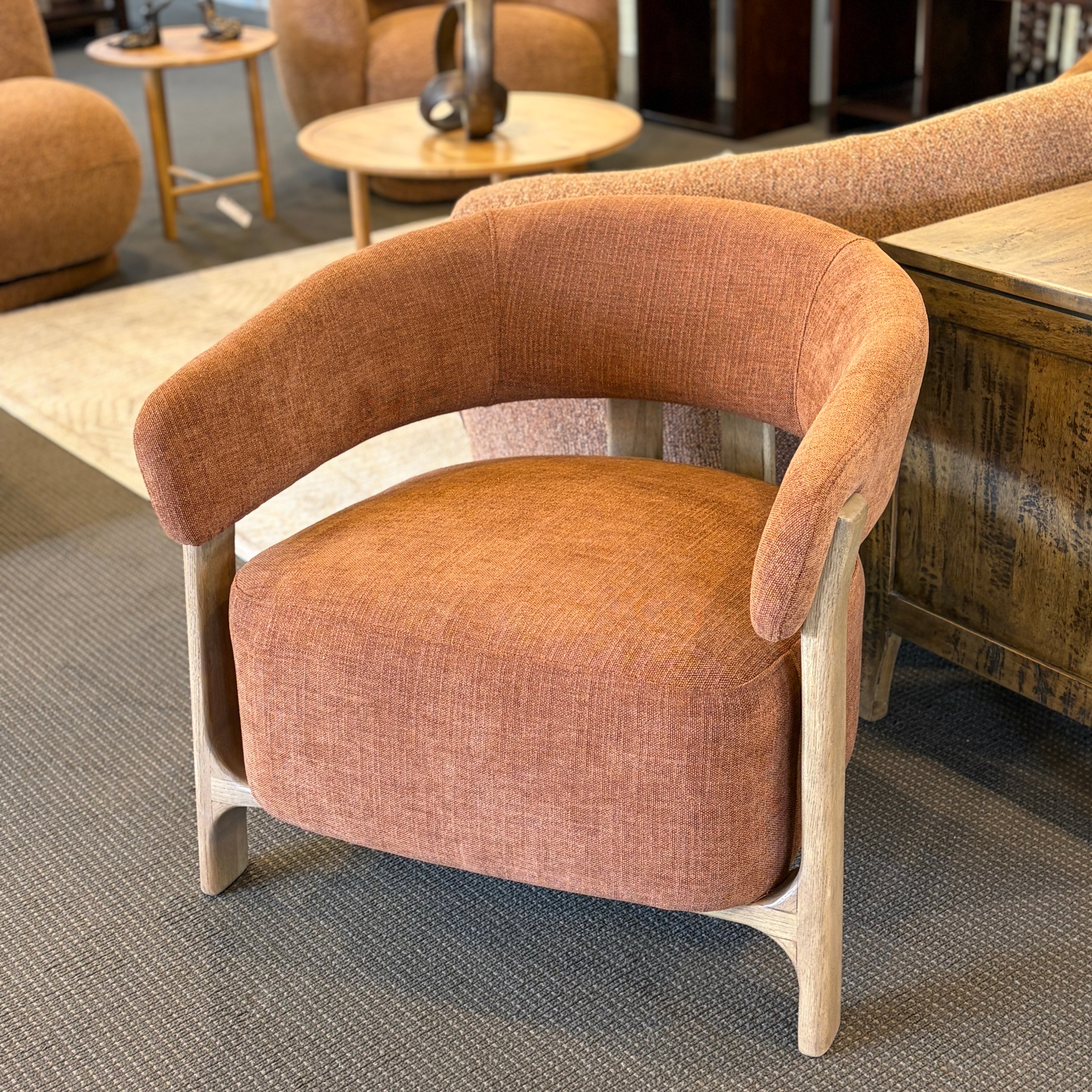 Angled view of the Aiden Chair in Burnt Orange, showcasing its curved upholstered seat and solid ash timber frame.