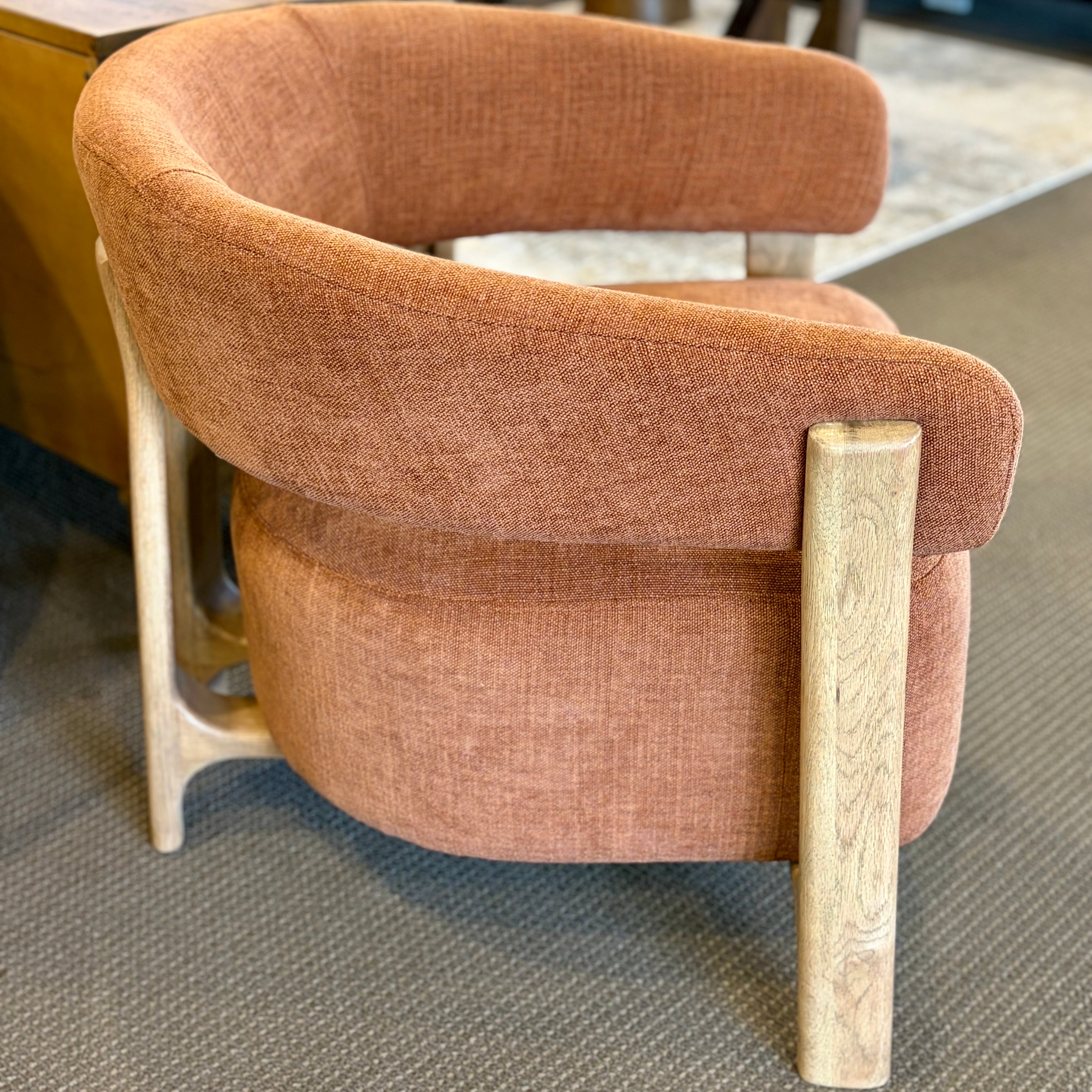 Side profile of the Aiden Chair in Burnt Orange with a curved upholstered seat and natural ash timber frame.