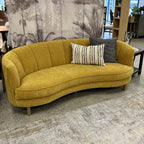 Bardot Sofa in Marigold styled in a contemporary showroom, demonstrating its curved design and bold colour.