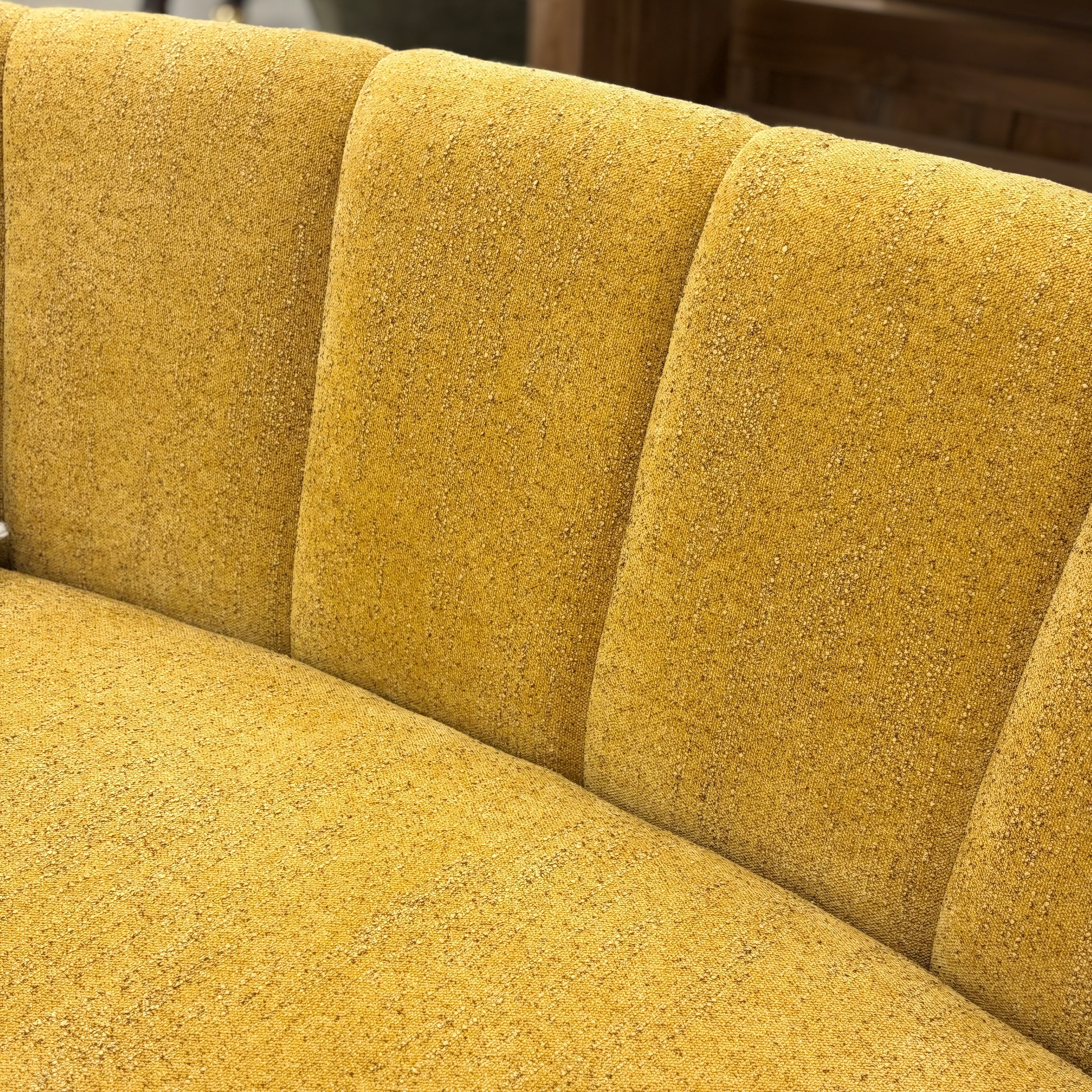 Close-up of the Bardot Sofa, showcasing the textured fabric back rest detail, piping and curved upholstery.