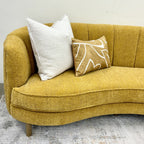 Bardot Sofa in Marigold styled with decorative cushions, highlighting its sculptural form and inviting seating.