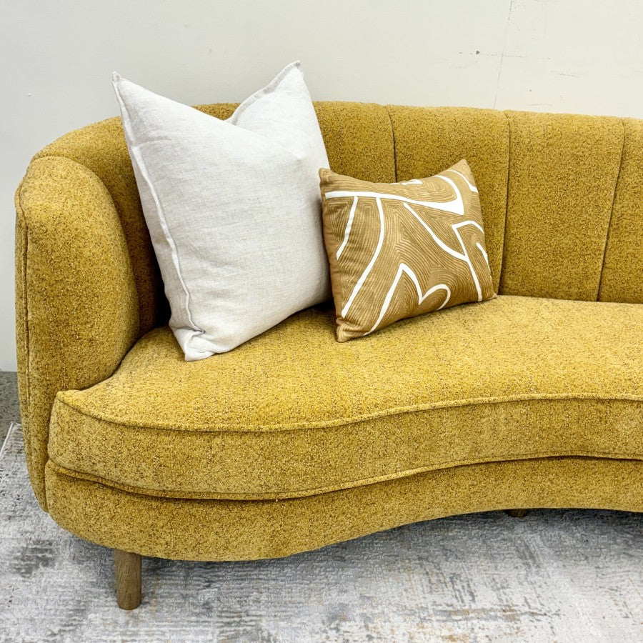 Bardot Sofa in Marigold styled with decorative cushions, highlighting its sculptural form and inviting seating.