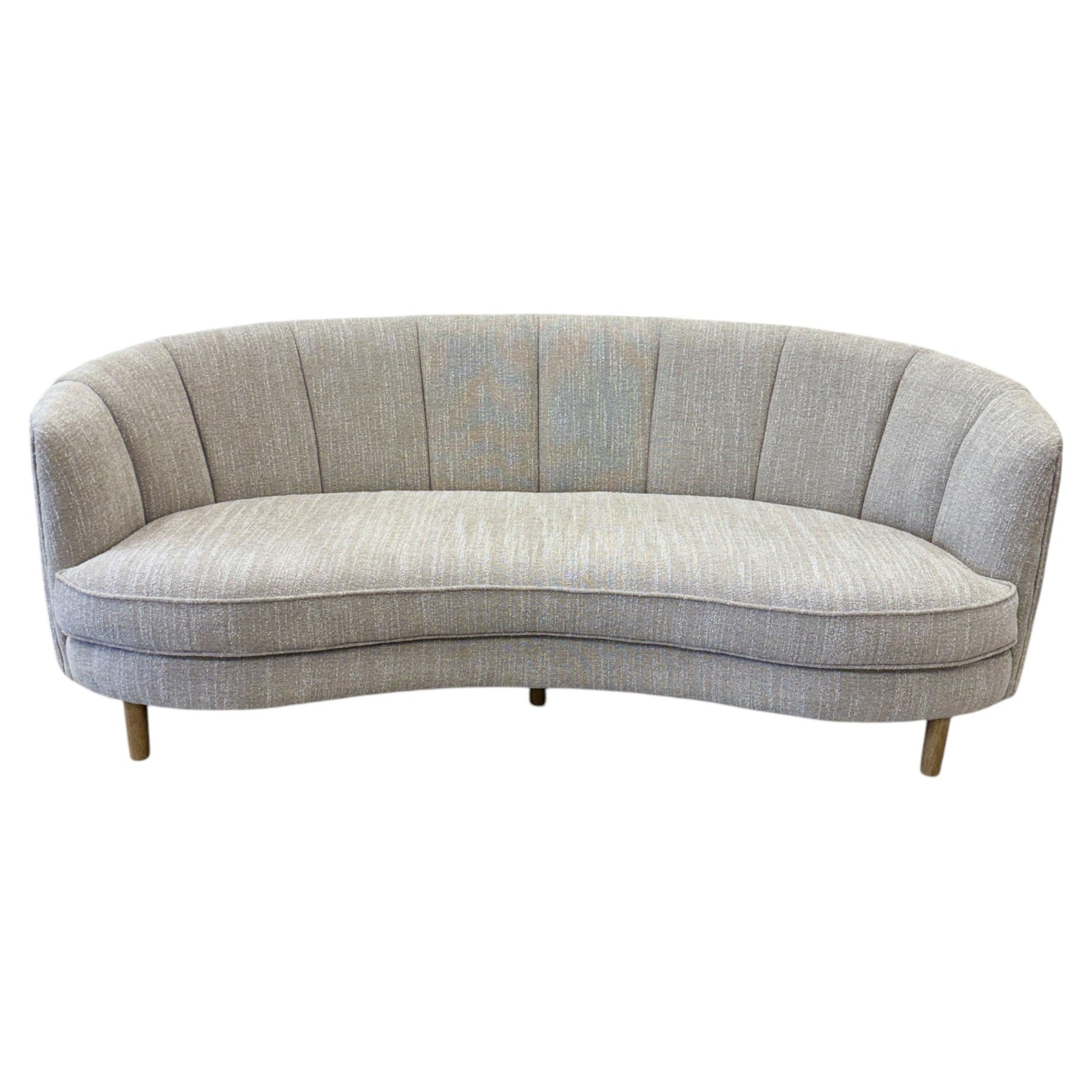 Angled view of the Bardot Sofa in Stone, showcasing its curved design, channel stitching and timber legs.