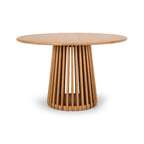 Side view of the Bur Round Dining Table in natural oak, showcasing the sculptural slatted pedestal base and clean Japandi-inspired design.