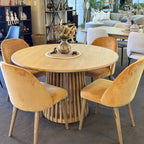 The Bur Round Dining Table styled with dining chairs in a contemporary dining setting, highlighting its warm oak finish and inviting round shape.