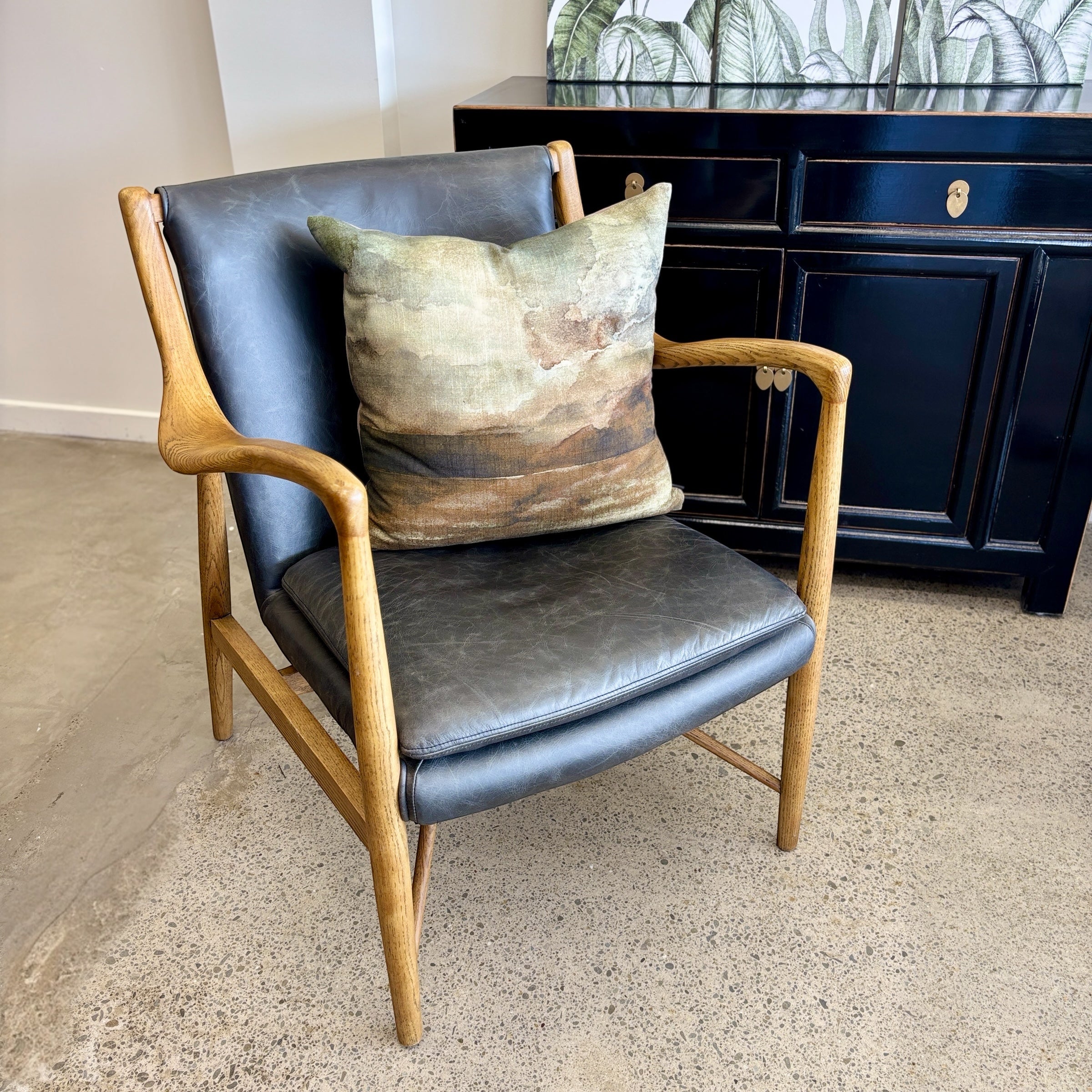 Angled view of the Coco Occasional Chair in black leather, highlighting its sculptural timber frame and contemporary silhouette.