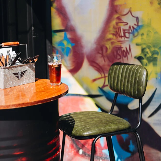 Close-up of the Datsun Bar Stool styled in a café, highlighting the ribbed upholstery, supportive backrest and quality finish.