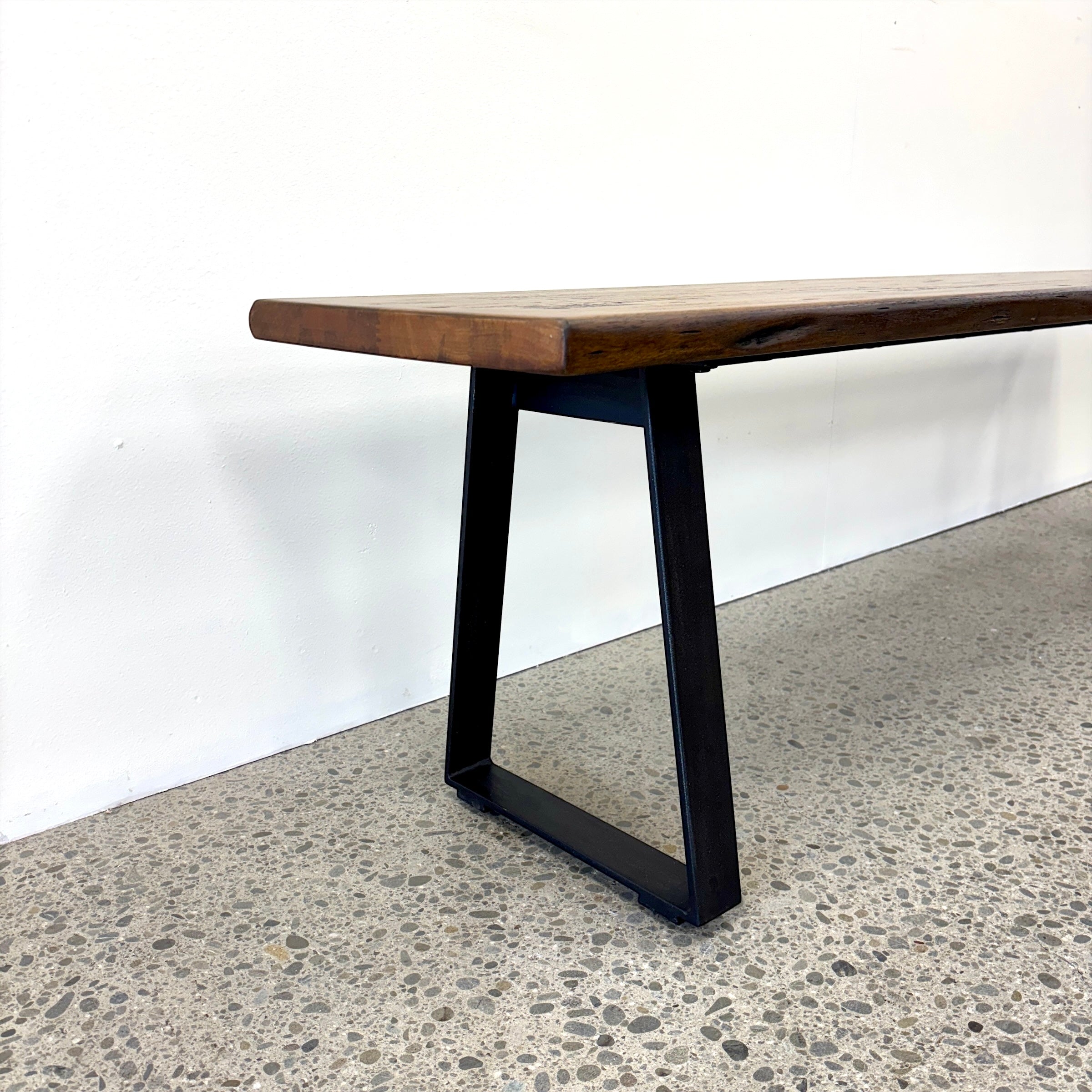 Detail of the Evolution Albany bench seat showing the black iron leg and mango wood seat