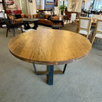 Angled view of the Evolution Round Dining Table in Albany, showcasing the solid mango wood top, iron base and rustic finish.