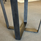 Close-up of the Evolution Round Dining Table's contemporary iron leg, highlighting the sturdy geometric base and durable powder-coated finish.