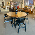 Evolution Round Dining Table in Albany styled with dining chairs, showcasing the solid mango wood top, iron base and rustic finish.