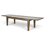 Angled view of the rustic timber extension dining table fully extended, showing its long rectangular top and tapered timber legs.