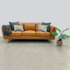 Fergus Sofa in Toffee leather styled with cushions, showcasing its warm leather finish and contemporary design.