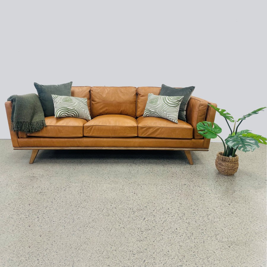 Fergus Sofa in Toffee leather styled with cushions, showcasing its warm leather finish and contemporary design.
