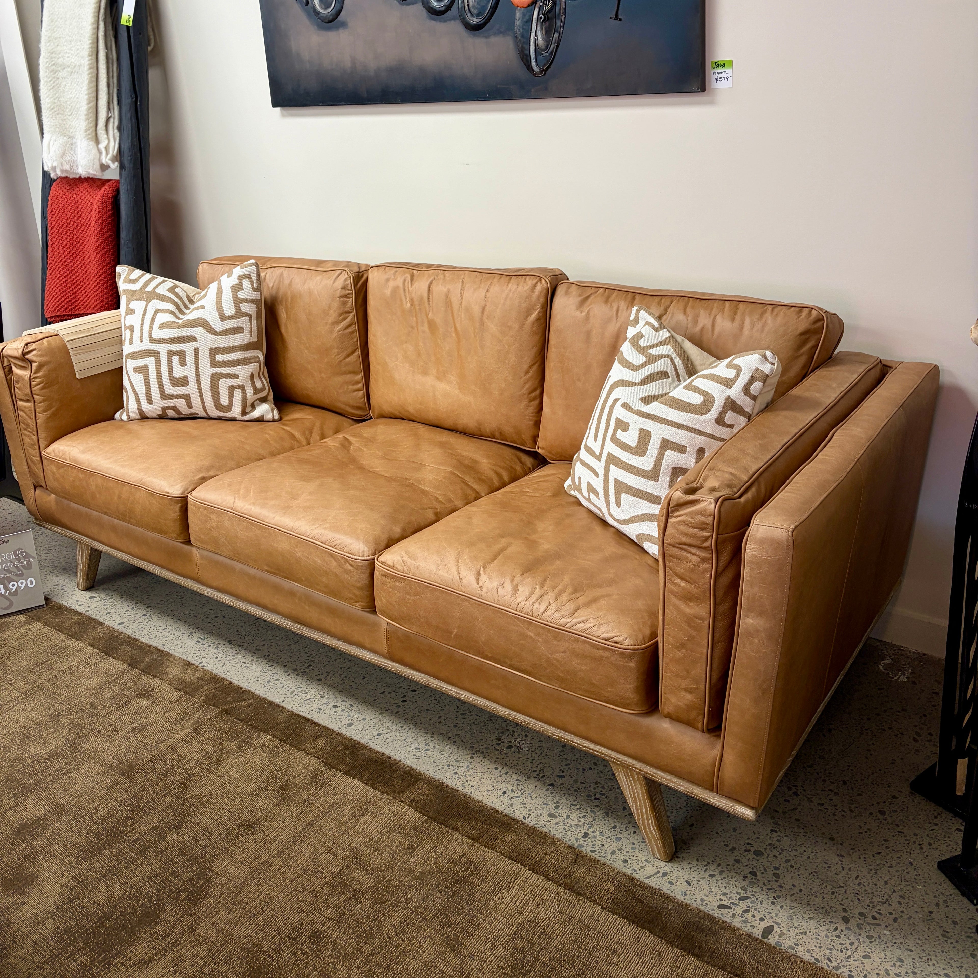 Fergus Sofa in Toffee leather styled in a contemporary showroom with complementary furniture and décor.