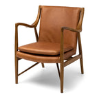 Angled view of the Finn Occasional Chair in Tan, showcasing its sculptural solid ash timber frame and premium aniline leather upholstery.