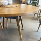 Side view of the Florence Round Dining Table in Natural, highlighting the slim profile, tapered legs and solid timber construction.