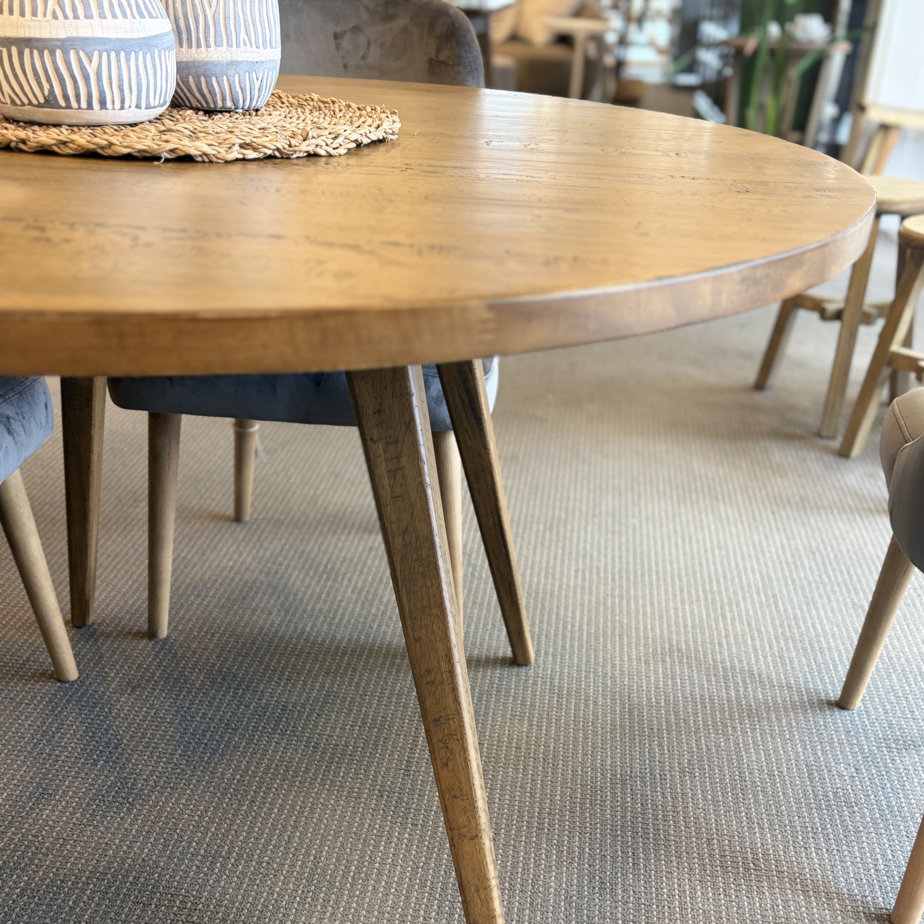 Side view of the Florence Round Dining Table in Natural, highlighting the slim profile, tapered legs and solid timber construction.