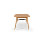 End detail of the Flow Dining Table, showcasing the bevelled tabletop edge, solid oak construction and tapered leg design.