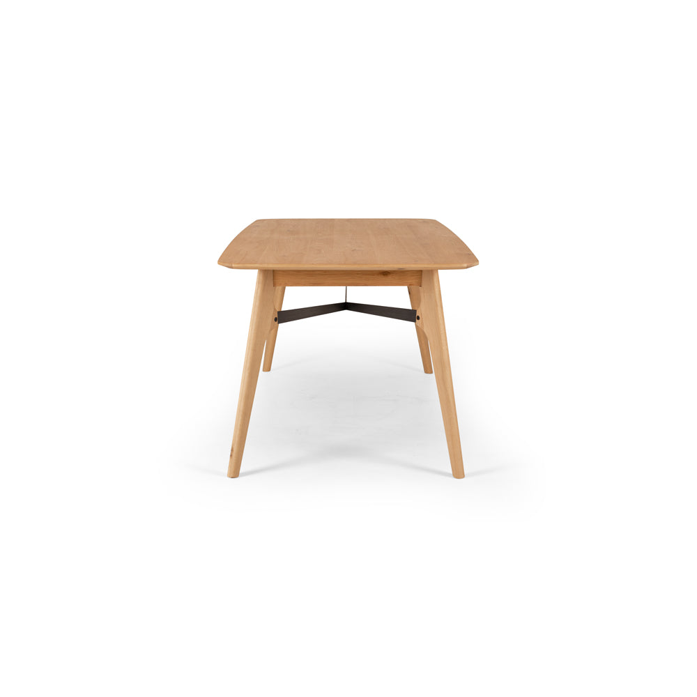 End detail of the Flow Dining Table, showcasing the bevelled tabletop edge, solid oak construction and tapered leg design.