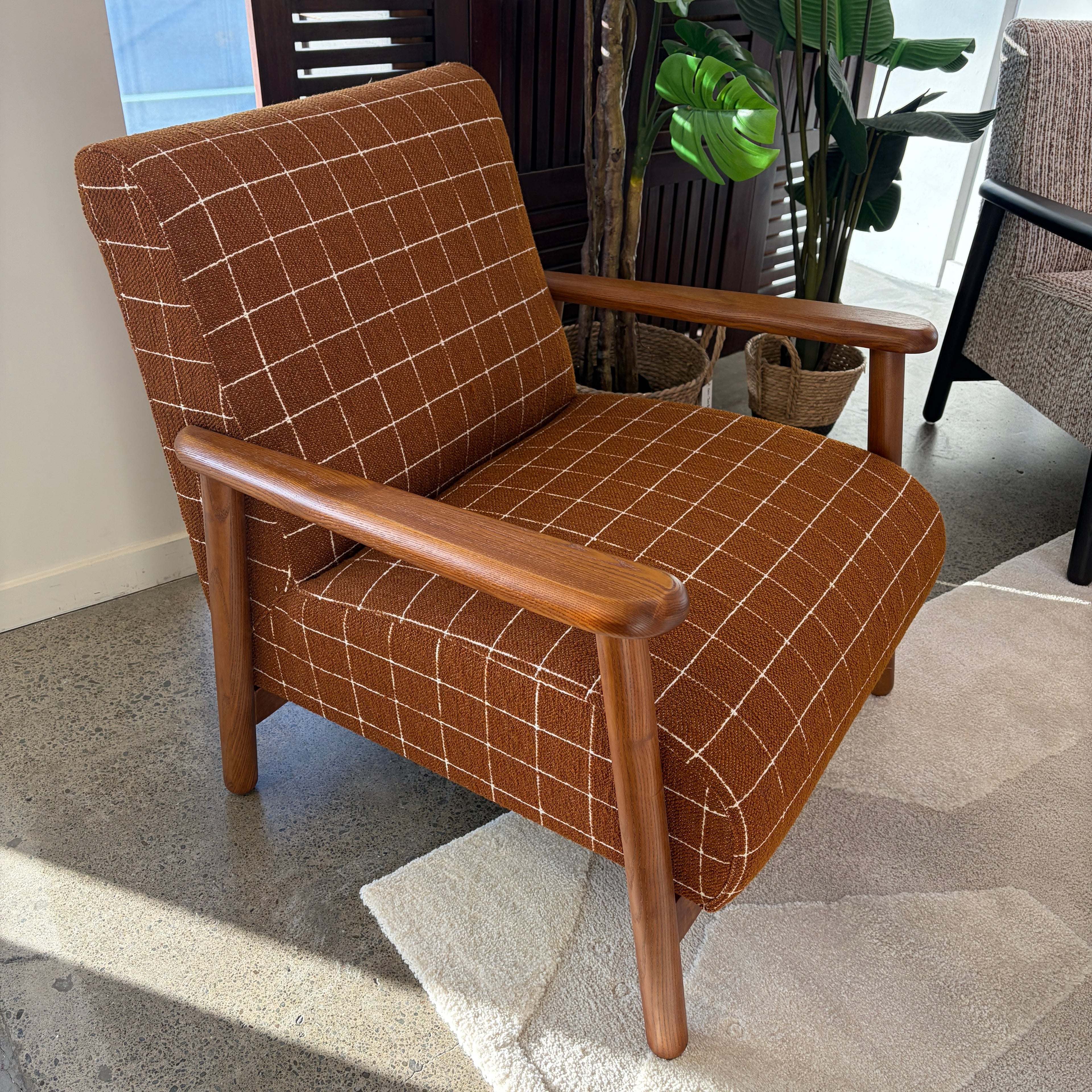 Angled view of the Frankie chair in Rust, showcasing its curved silhouette and upholstered seat.