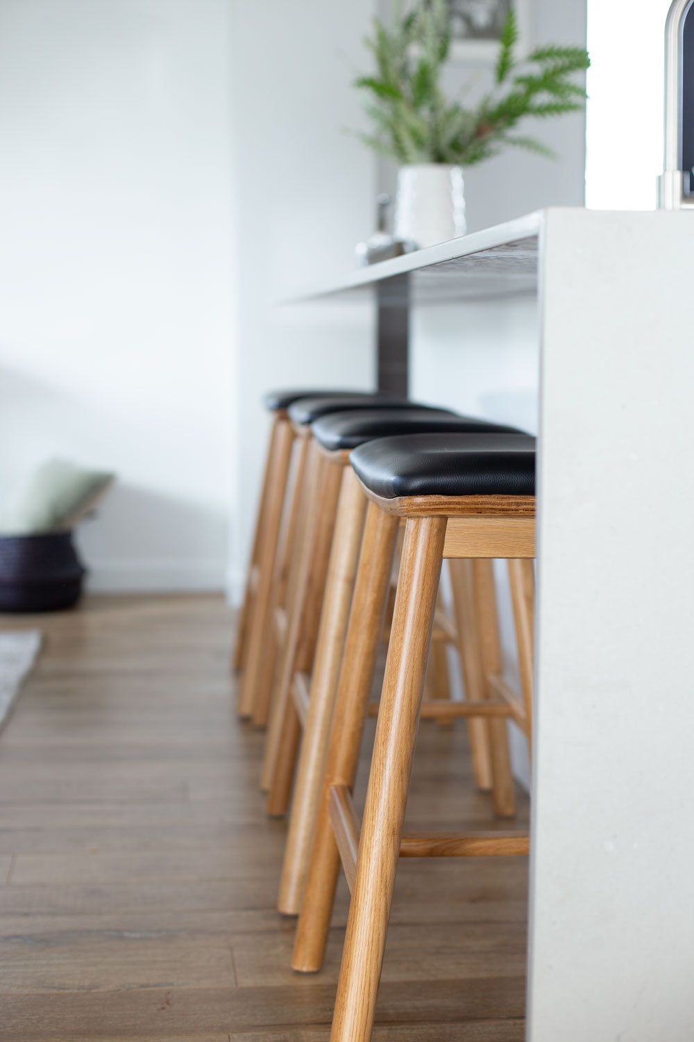 Hue Bar Stools in Natural Oak positioned along a modern kitchen island
