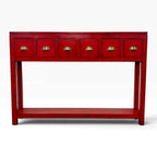 A red console table with six small drawers on the top panel, each featuring a gold-toned semicircular pull handle, and an open lower shelf, shown against a plain white background.