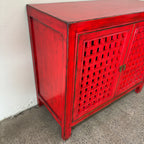 Close-up of antique-style metal handles on the red lattice cupboard doors