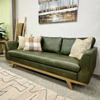 Angled view of the Lucca Sofa in Moss Green leather styled with cushions, highlighting its contemporary design and premium leather upholstery.