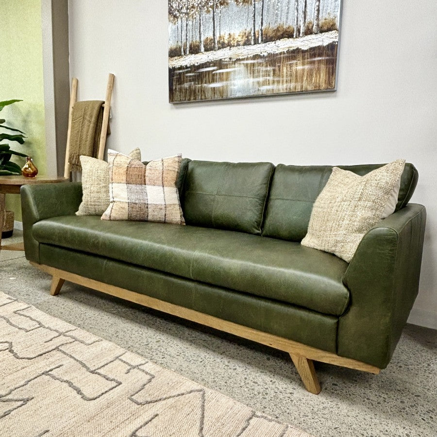 Angled view of the Lucca Sofa in Moss Green leather styled with cushions, highlighting its contemporary design and premium leather upholstery.