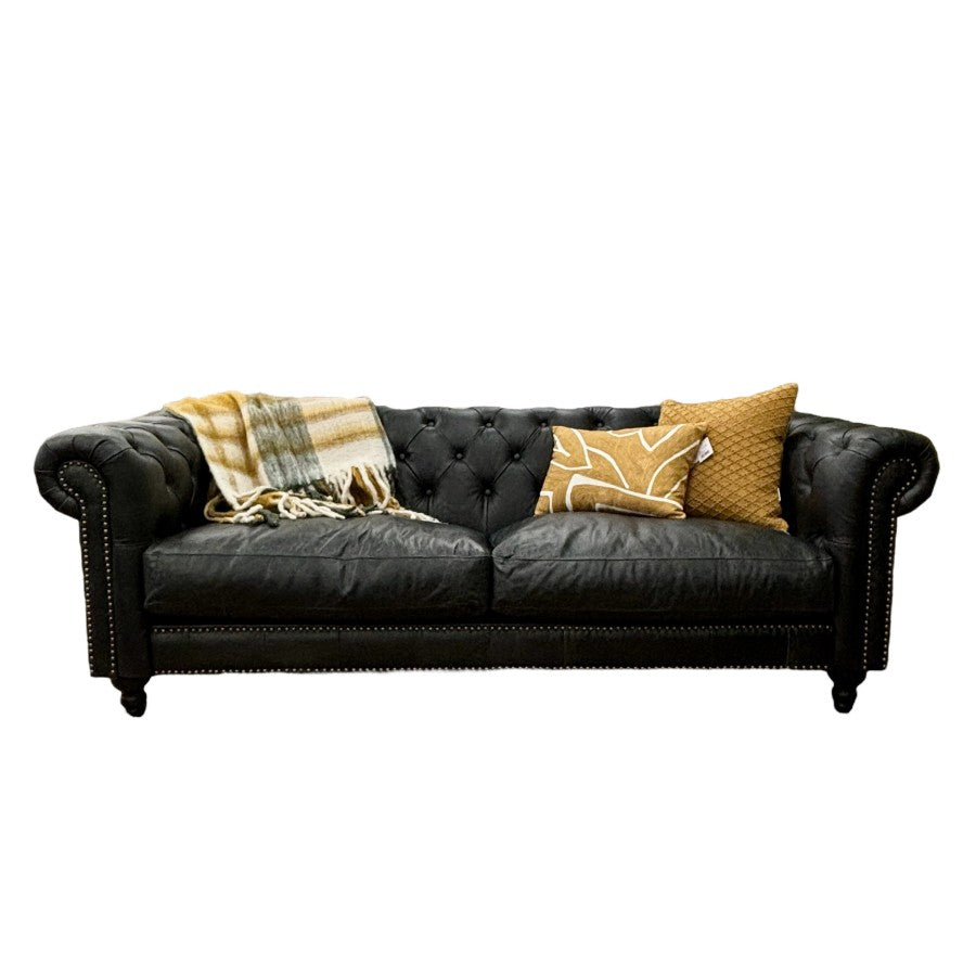 Maxwell Chesterfield sofa in black leather styled with decorative cushions and classic Chesterfield detailing.
