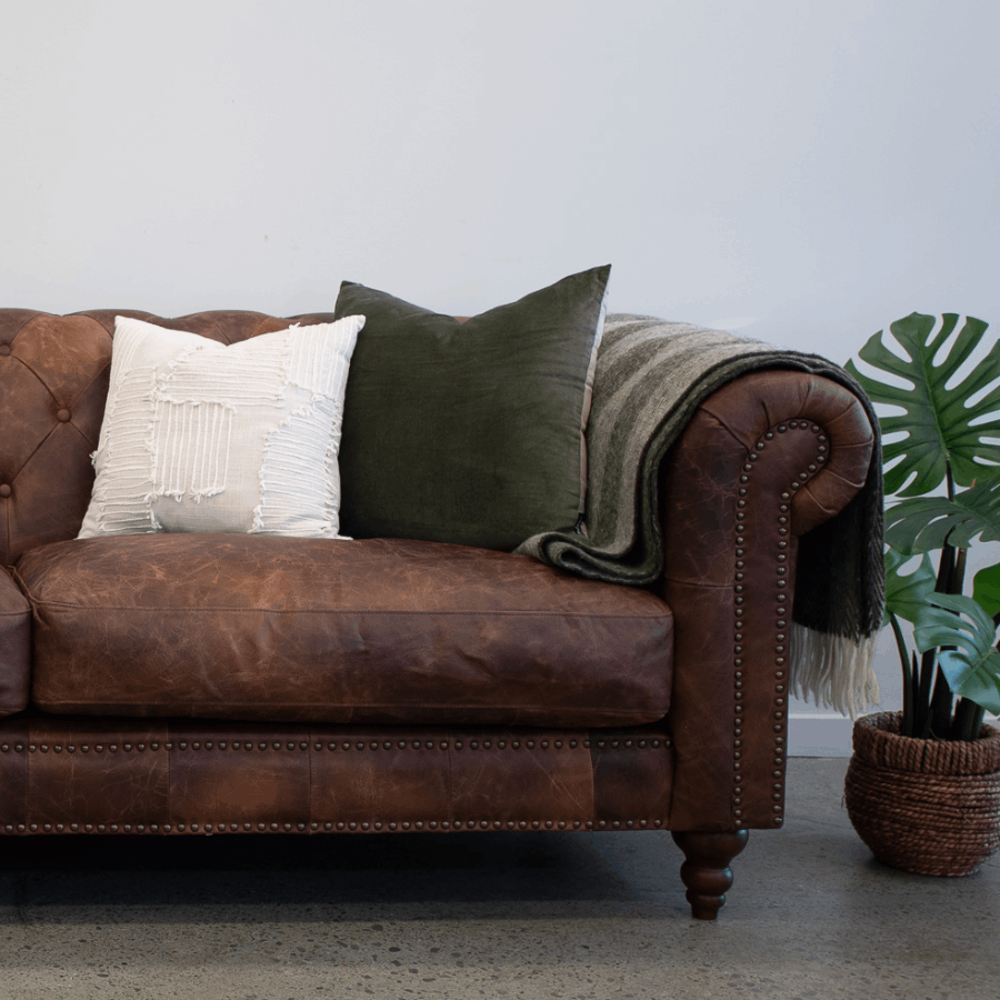 Close-up of the Maxwell Chesterfield sofa's rolled arm with deep button tufting and rich brown leather and stud detailing.