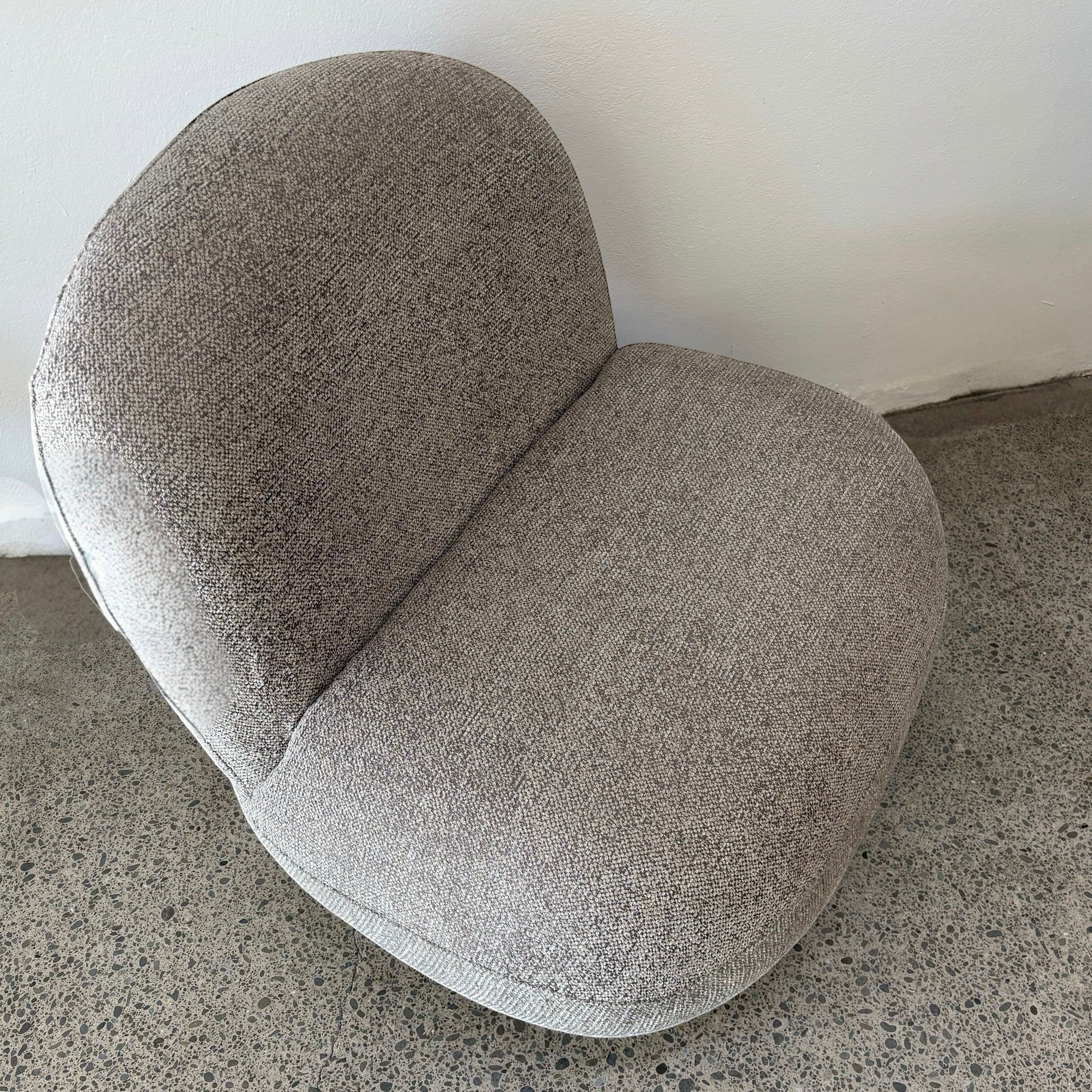 Angled view of the Milo Swivel Chair in Latte with a contemporary curved design and textured fabric upholstery.