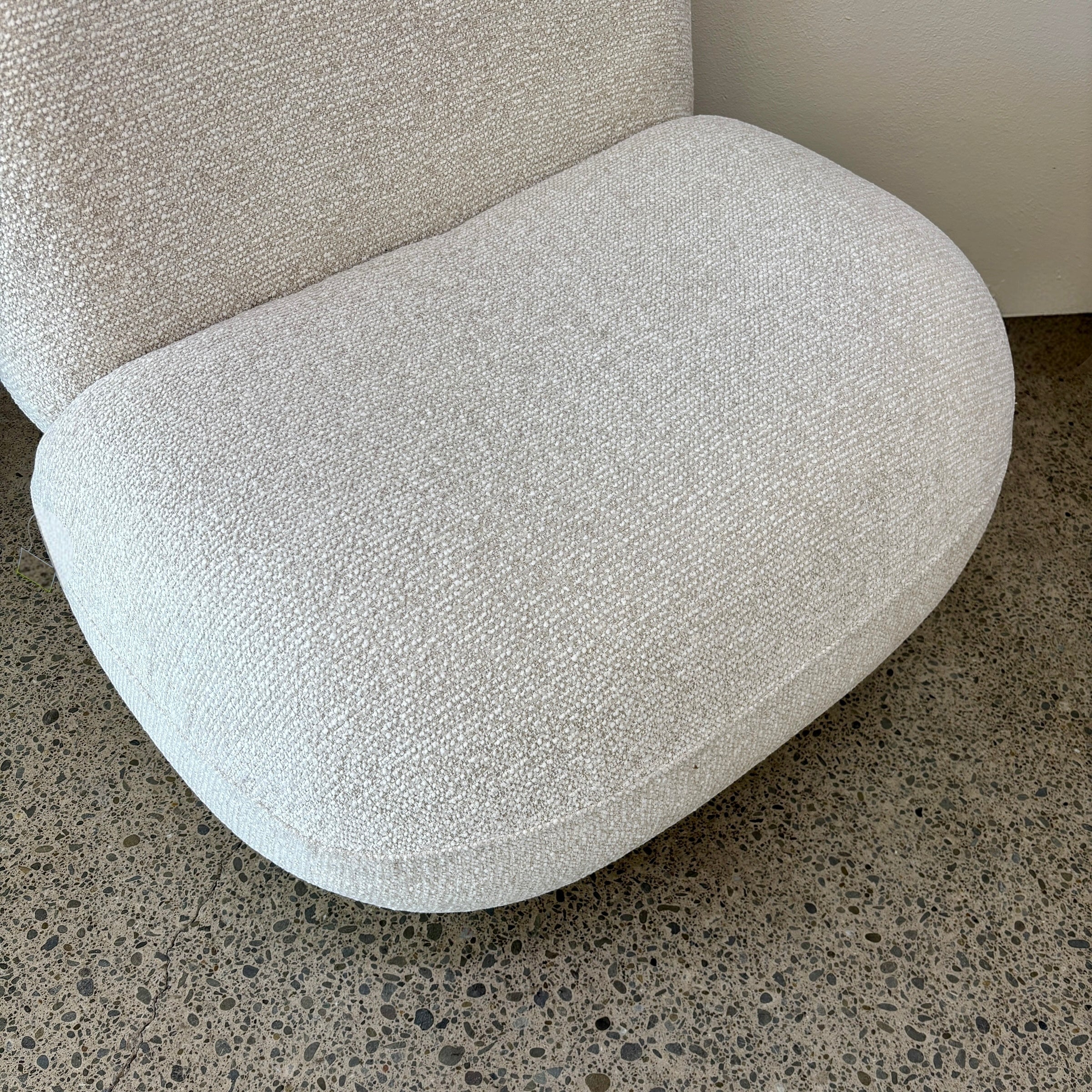 Angled view of the Milo Swivel Chair in Salt with a curved contemporary design and textured fabric upholstery.