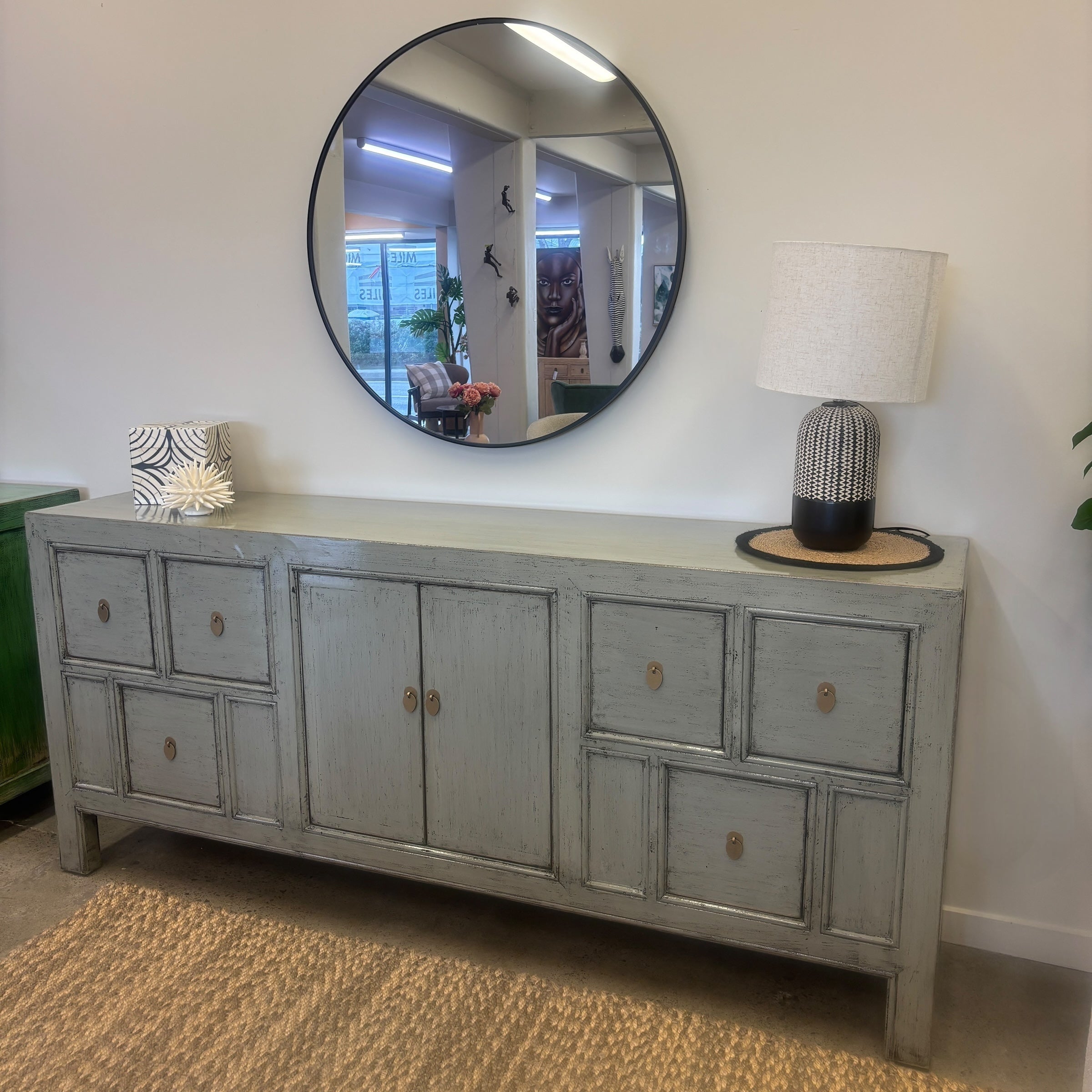 Angled view of Morocco glossy grey sideboard styled with mirror, lamp and homewares