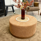 Copper Nova Ottoman styled in front of a tan leather sofa in a living room setting