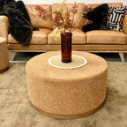 Nova Ottoman in copper styled as a round coffee table in a contemporary living room setting