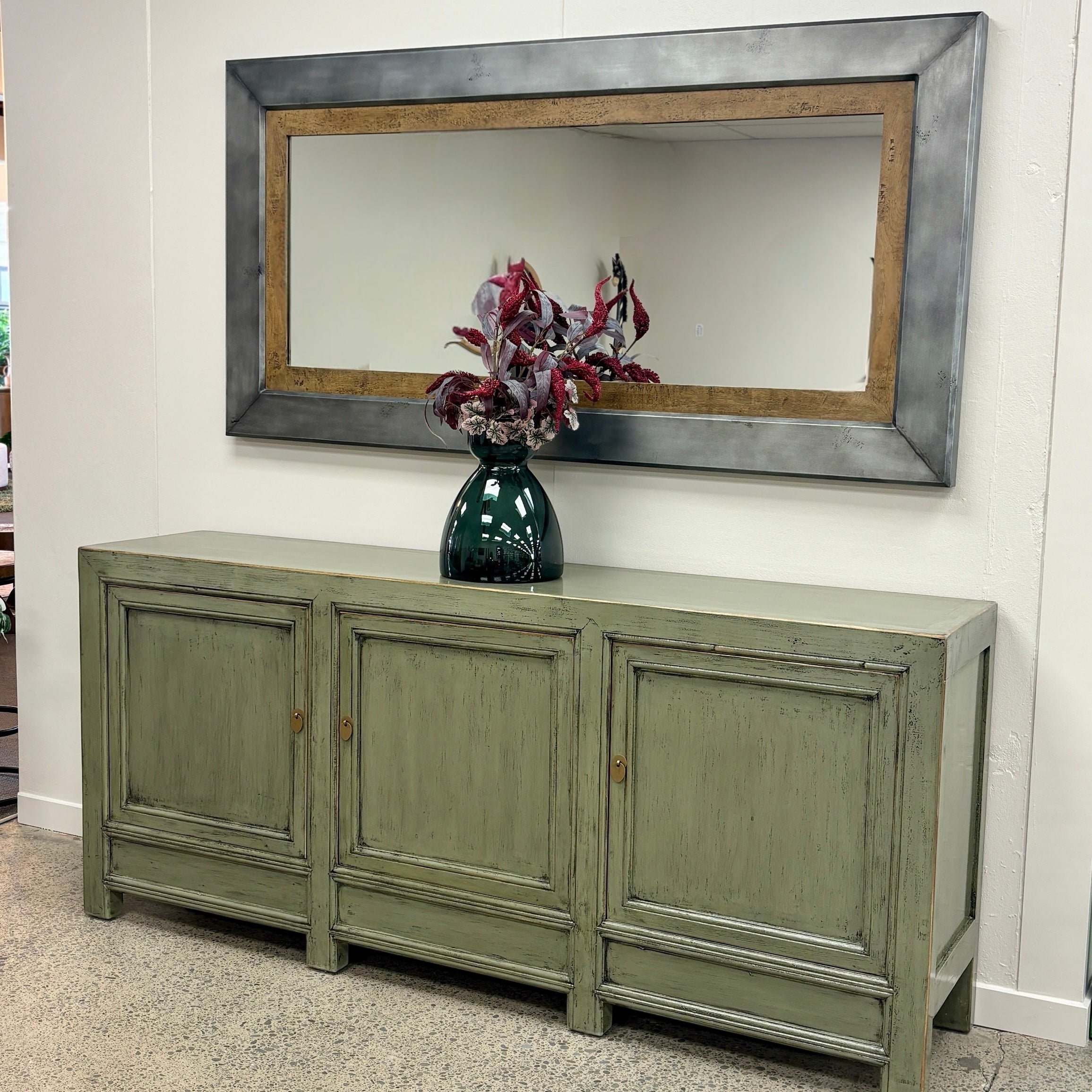 Patrick Sideboard in smoke finish styled with a mirror, vase and decorative flowers