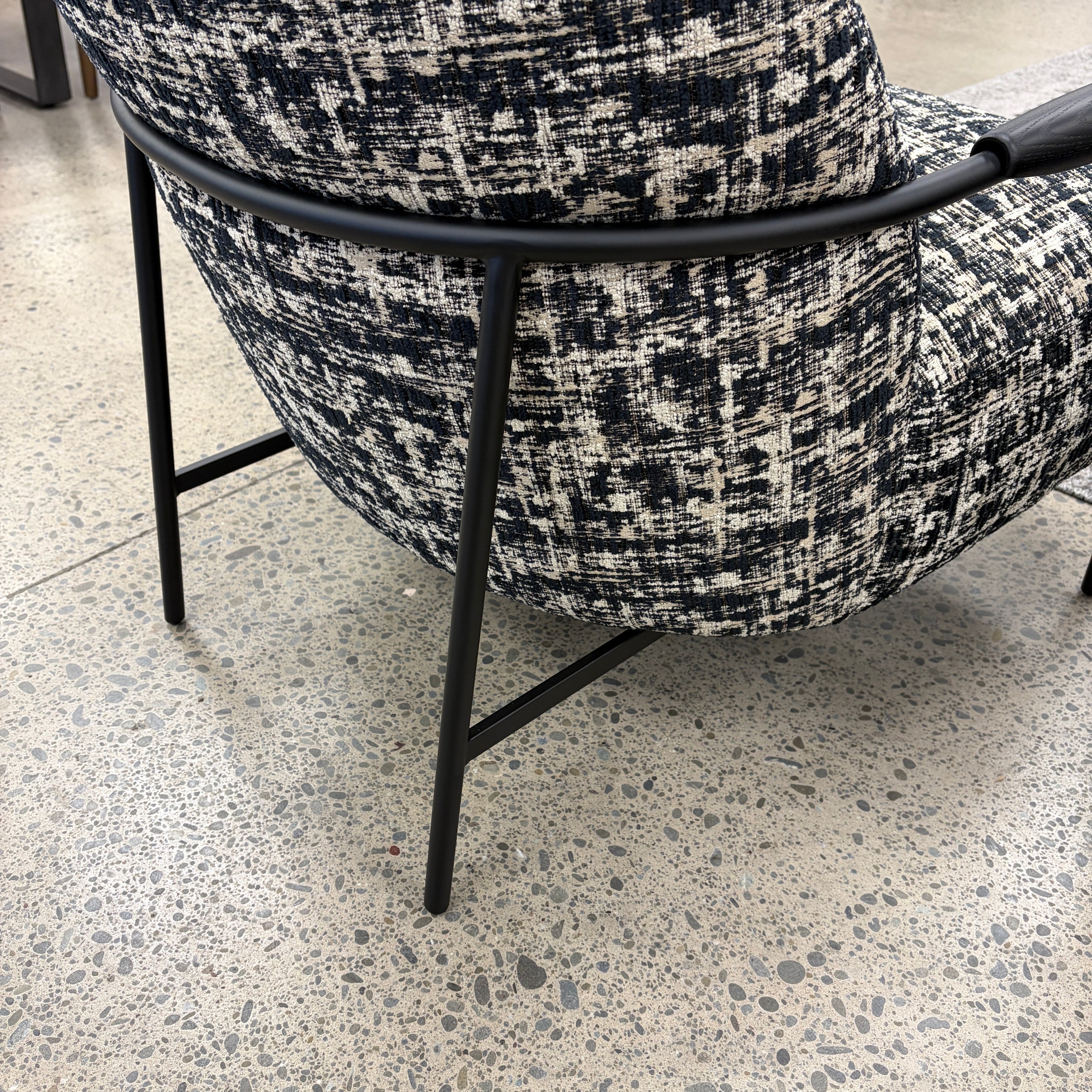 Close-up of the Portia armchair, featuring textured fabric and metal frame.