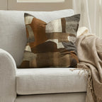 Sienna Cushion Chocolate styled on a neutral armchair with warm earthy abstract pattern