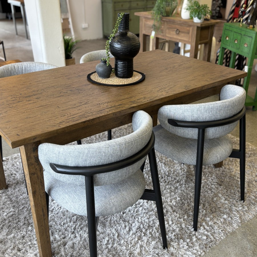 Sienna Dining Table in a Smokehouse finish displayed in a contemporary furniture showroom.