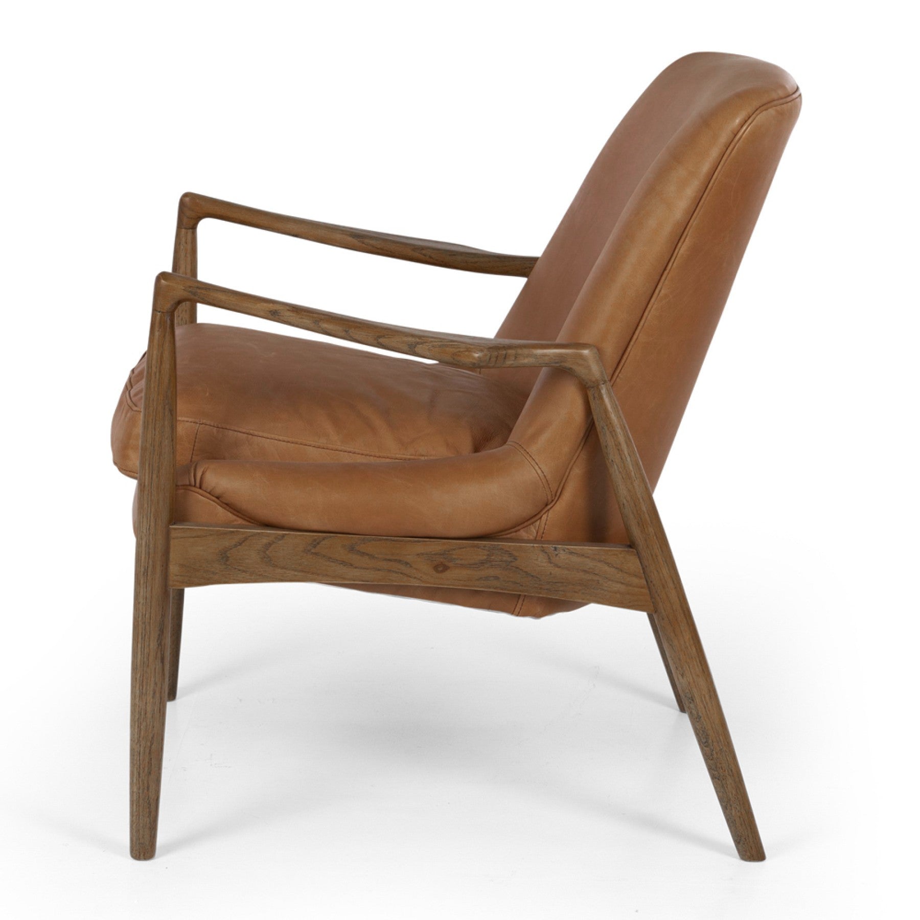 Side profile of the Steiner Occasional Chair in Cognac with a solid oak frame and premium aniline leather upholstery.